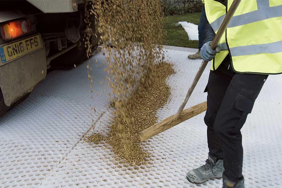 Worker filling Core Edge gravel grids with gravel to create a smart new gravel driveway