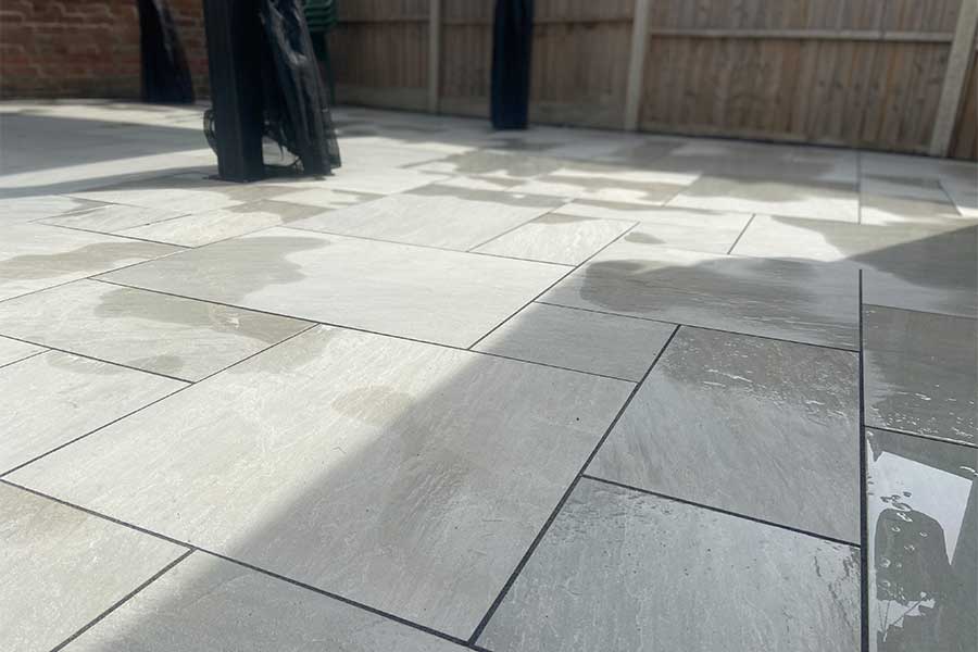 Large patio featuring grey sandstone effect porcelain paving slabs from the AWBS Exclusive range