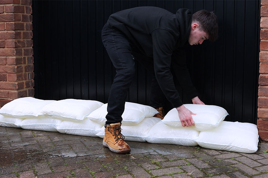 A man protecting the entrance to a domestic garage door with innovative Fernoco Floodbags to make a flood barrier